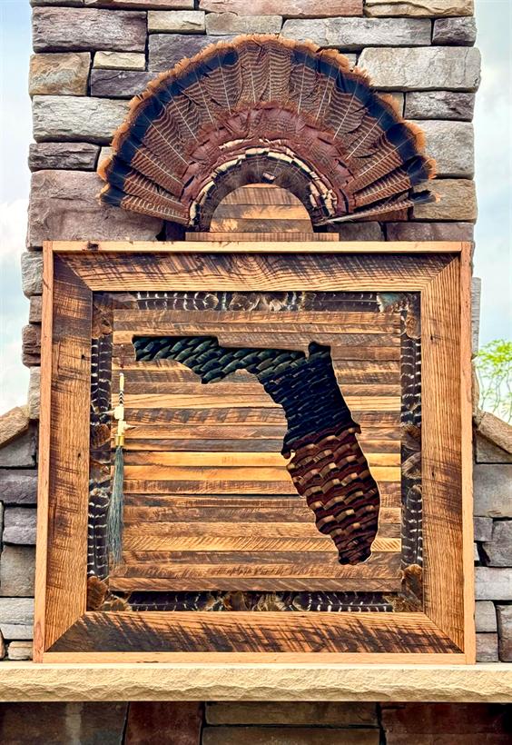 Florida State Frame — the state cut from reclaimed oak over wild turkey feathers, a full fan mounted above on a stone fireplace