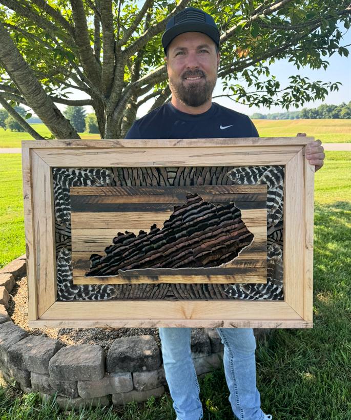 Mark Cooke holding a Kentucky State Frame in spalted maple, turkey feathers filling the state silhouette
