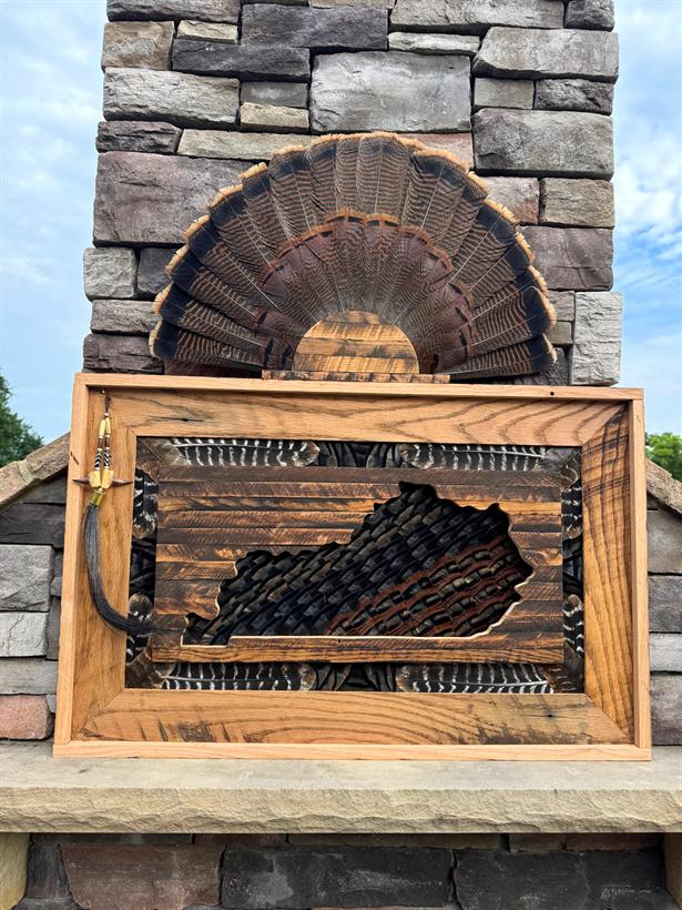 Kentucky State Frame in reclaimed oak with a full turkey fan mounted above, photographed on an outdoor stone fireplace